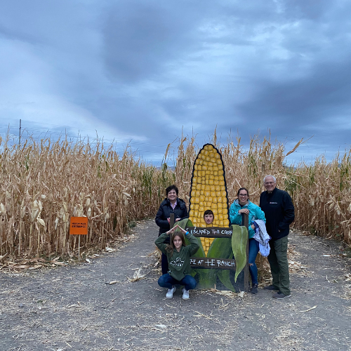 A family standing in front of a corn maze at Cross E Ranch