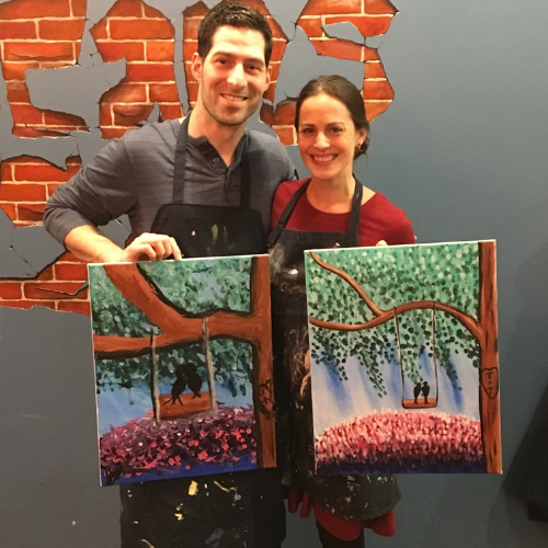 Couple showing off their paintings from a paint night date